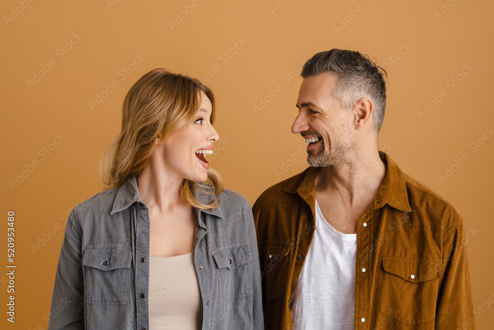 White couple wearing shirts smiling and looking at each other White couple wearing shirts smiling and looking at each other