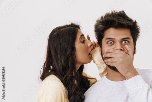 Young indian woman whispering secret to her boyfriend