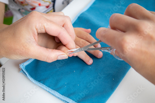 Children's manicure. Female hands cut nails on children's hands with manicure scissors