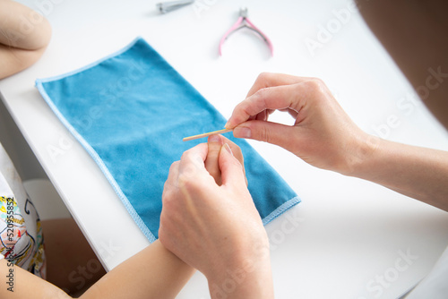 Women s hands on a child s hand file their nails with a nail file. Top view  flat lay