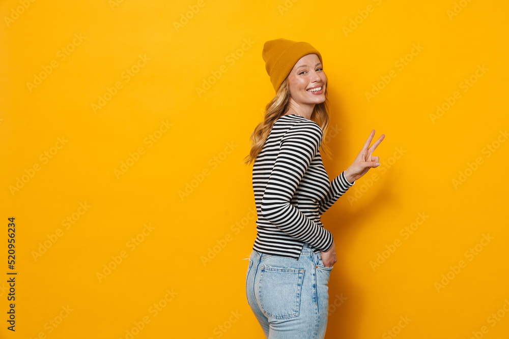Young blonde woman wearing hat smiling and gesturing at camera Young blonde woman wearing hat smiling and gesturing at camera