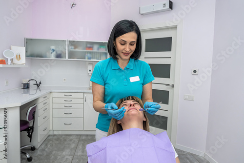 two dentists women in special clothes look at the teeth of a patient with caries