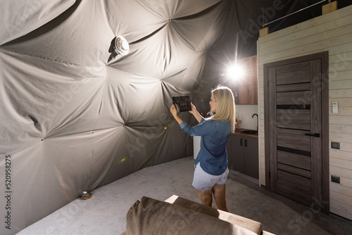 woman with tablet turning on ventilation system as a recuperator for fresh indoor air quality, smart home