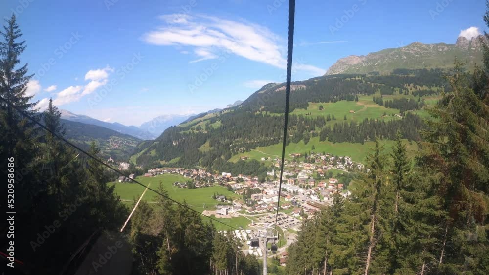 Cable car ride in the canton of Grisons. The gondola lift descends into the valley. You can see the small village in the valley and the beautiful nature of Switzerland with its hiking trails Cable car ride in the canton of Grisons. The gondola lift descends into the valley. You can see the small village in the valley and the beautiful nature of Switzerland with its hiking trails