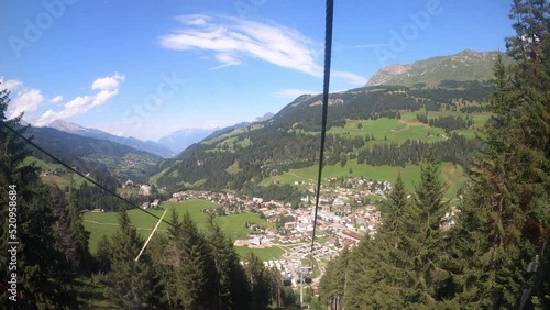 Cable car ride in the canton of Grisons. The gondola lift descends into the valley. You can see the small village in the valley and the beautiful nature photo