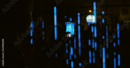 Young female recording video of neon lights performance show at night with smartphone. Photography, video, lights entertainment and technology concept. High quality 4k footage