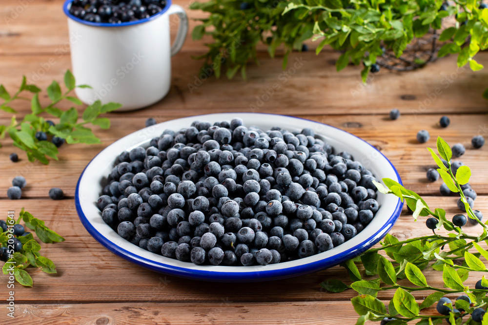 Frozen blueberries in a metal bowl on wooden table Frozen blueberries in a metal bowl on wooden table