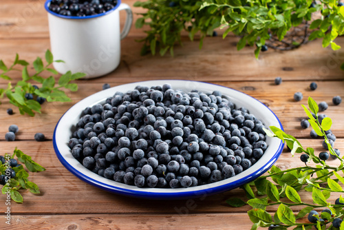 Frozen blueberries in a metal bowl on wooden table