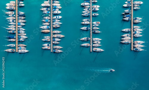 Aerial view of luxure yachts and motorboats moored in a port with clear blue water in summer. Top view from drone of sailboats and various speed boats in dock. Pula, Croatia photo