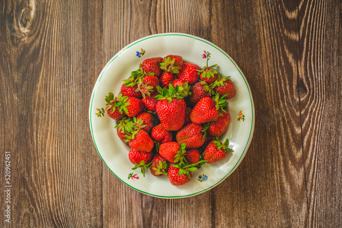 Strawberries background.Fresh strawberry on plate.Food background.Freshly harvested strawberries on table,top view.Ripe organic sweet strawberry.Summer fruit from top.Tasty vegan snack with vitamins