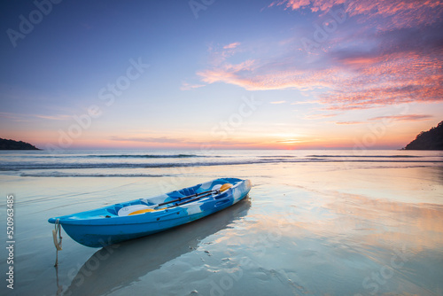 Blue canoe on the beach with sunset at Trat province, Thailand.