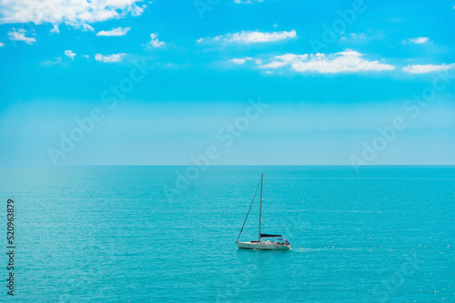 A sailboat sailing in selective focus on a calm turquoise azure sea against a blue cloudy sky. Yacht trip. Relaxation, tranquility, relaxation.