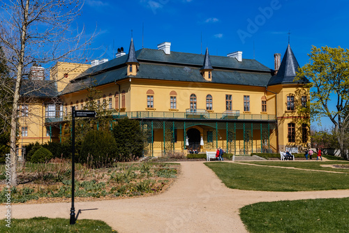 Slatinany, Czech Republic, 17 April 2022: classical chateau or romantic yellow castle surrounded by a garden, ancient aristocratic residence with park in summer sunny day