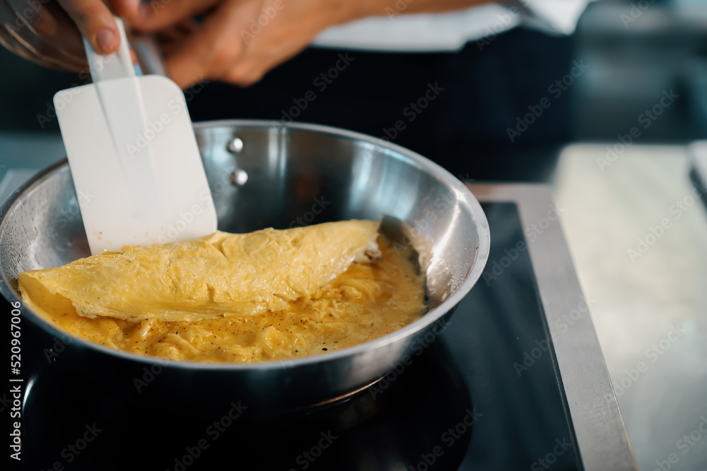 Close-up of a chef preparing a french omelette on a frying pan in