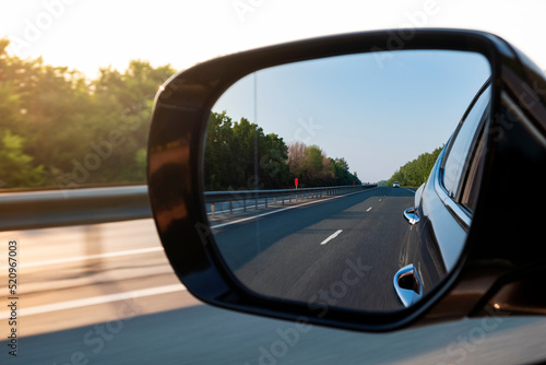 Look in the rear view mirror of a car. Car driving on the road.