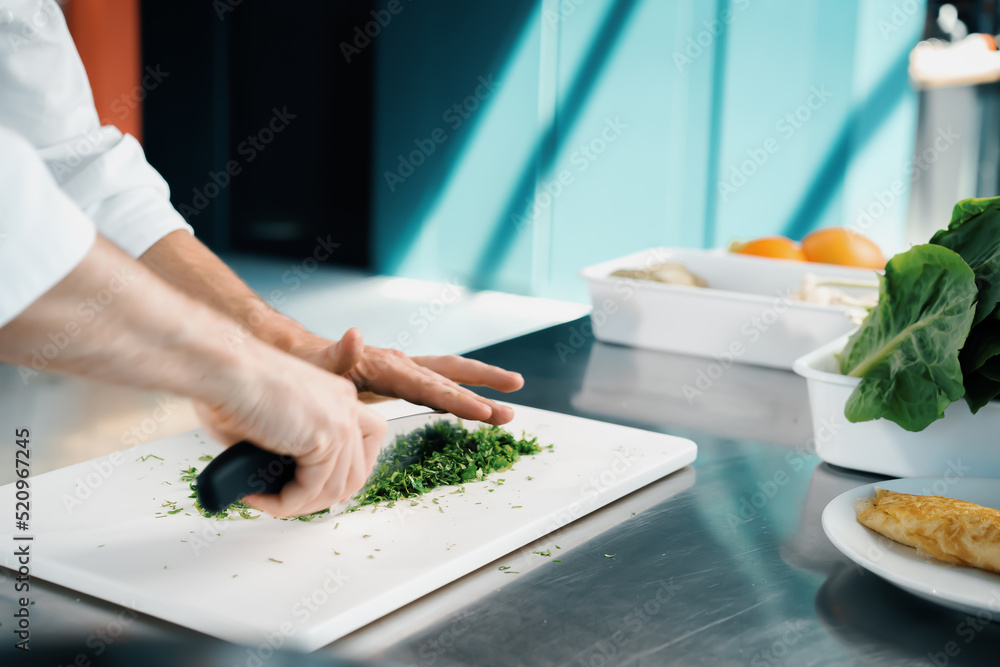 Close-up of a chef finely chopping herbs in a professional kitchen