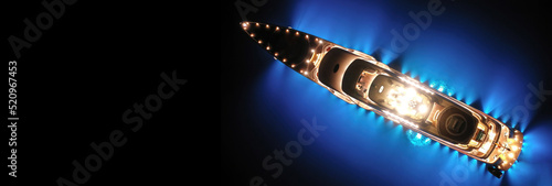 Aerial drone ultra wide panoramic night shot with copy space of beautiful latest technology modern led illuminated luxury mega yacht anchored in tropical exotic bay with deep blue sea