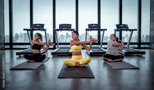Group of Slim Women and fat woman in sportswear doing yoga on mat during an exercise class with a group of friends at the gym, make muscle body building and good healthy concept.