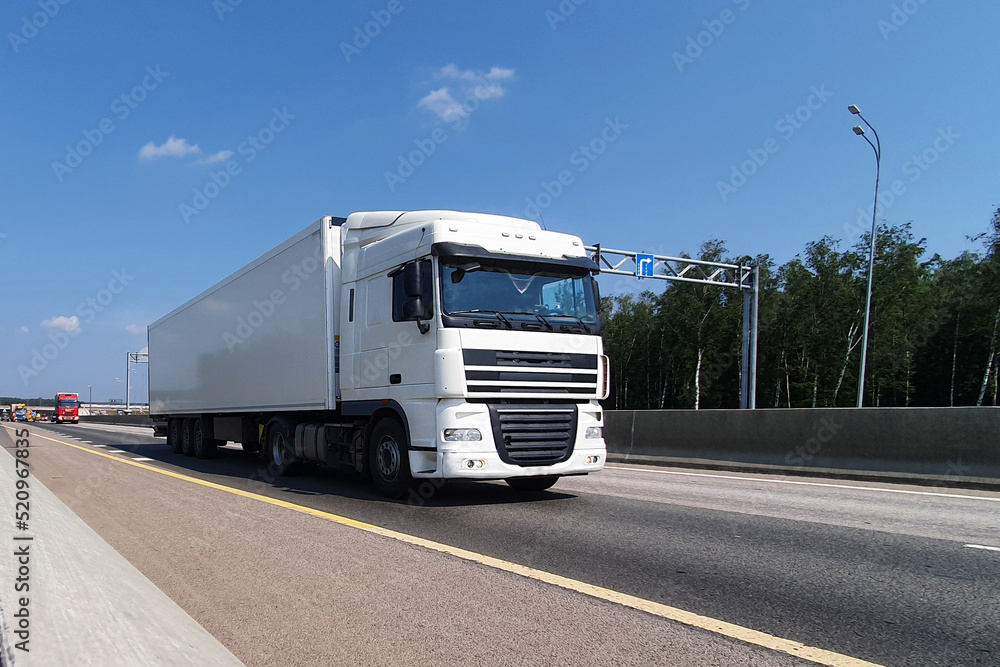 A white truck is moving along the autobahn. Freight, container transportation.