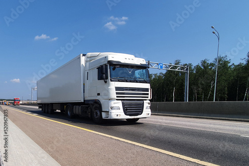 A white truck is moving along the autobahn. Freight, container transportation.