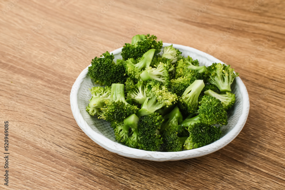 Fresh raw broccoli ready to cook served on white plate on wooden background. Fresh raw broccoli ready to cook served on white plate on wooden background.
