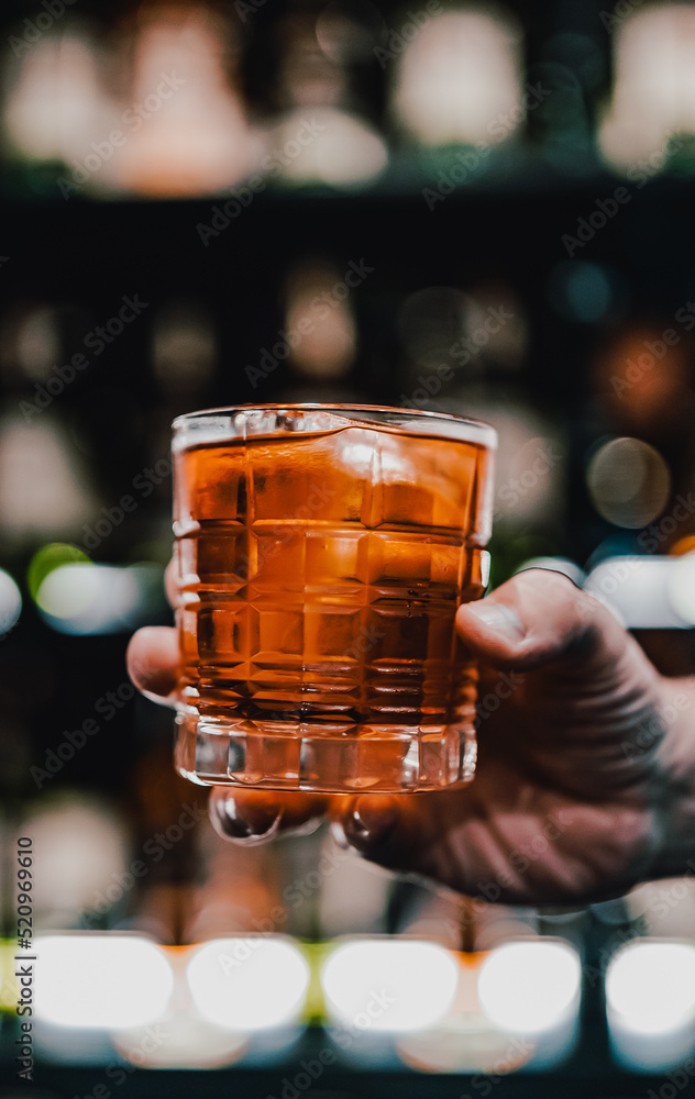 male hand holding a glass of whiskey in a bar