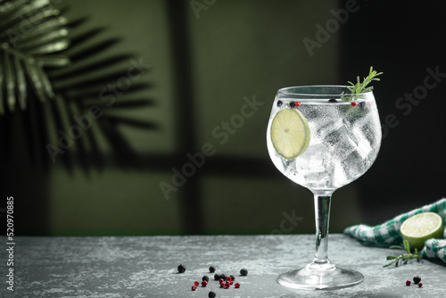 Gin tonic cocktail and shadows next to the window on dark concrete background. photo