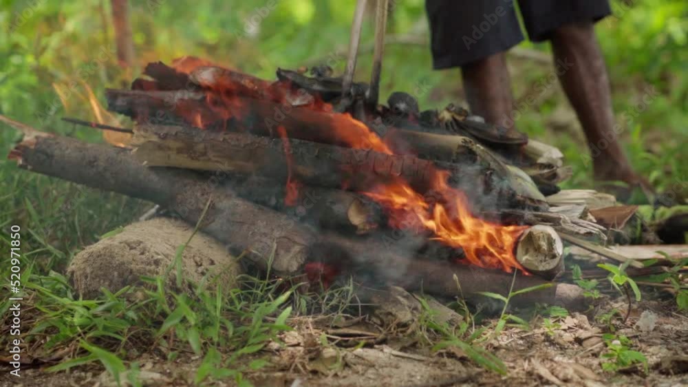 A hand is twisting the Green Banana while grilled with wood. A hand is twisting the Green Banana while grilled with wood.