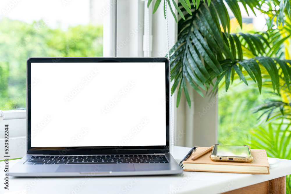 Mockup of laptop computer with empty screen with notebook,ice coffee and smartphone on table side the window in the coffee shop at the cafe,White screen Mockup of laptop computer with empty screen with notebook,ice coffee and smartphone on table side the window in the coffee shop at the cafe,White screen
