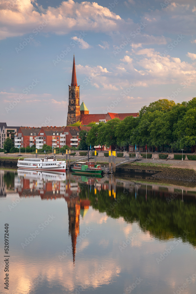 Bremen, Germany. Cityscape image of riverside Bremen, Germany with reflection of the St. Stephani Church in Weser River at summer sunrise.