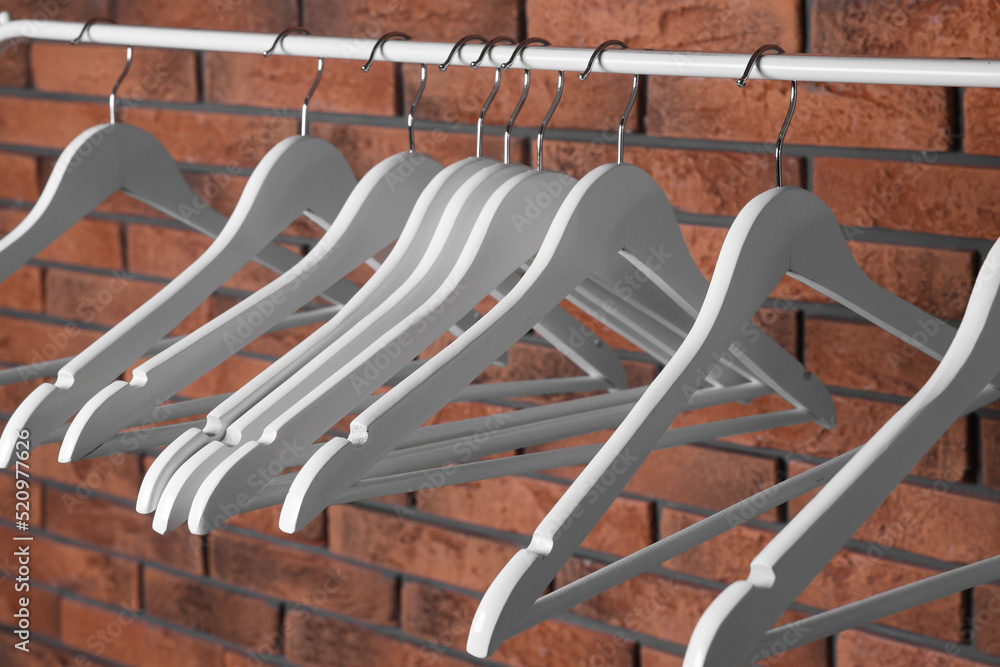 White clothes hangers on rail near red brick wall White clothes hangers on rail near red brick wall