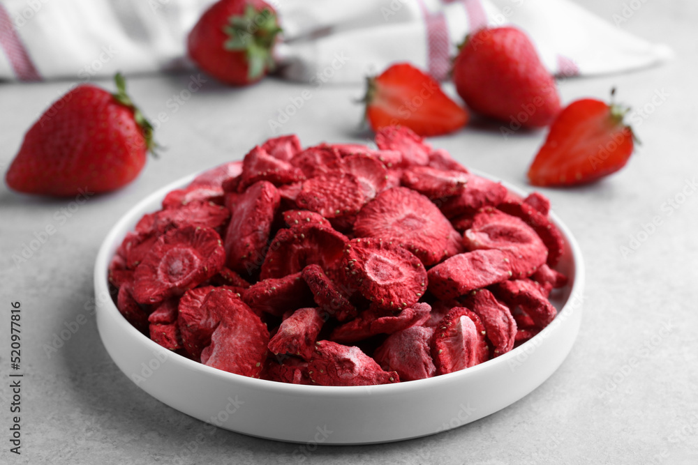 Freeze dried and fresh strawberries on light grey table, closeup Freeze dried and fresh strawberries on light grey table, closeup
