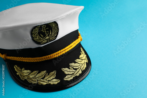 Peaked cap with accessories on light blue background, closeup. Space for text