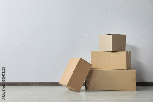 Many closed cardboard boxes on floor near white wall, space for text. Delivery service