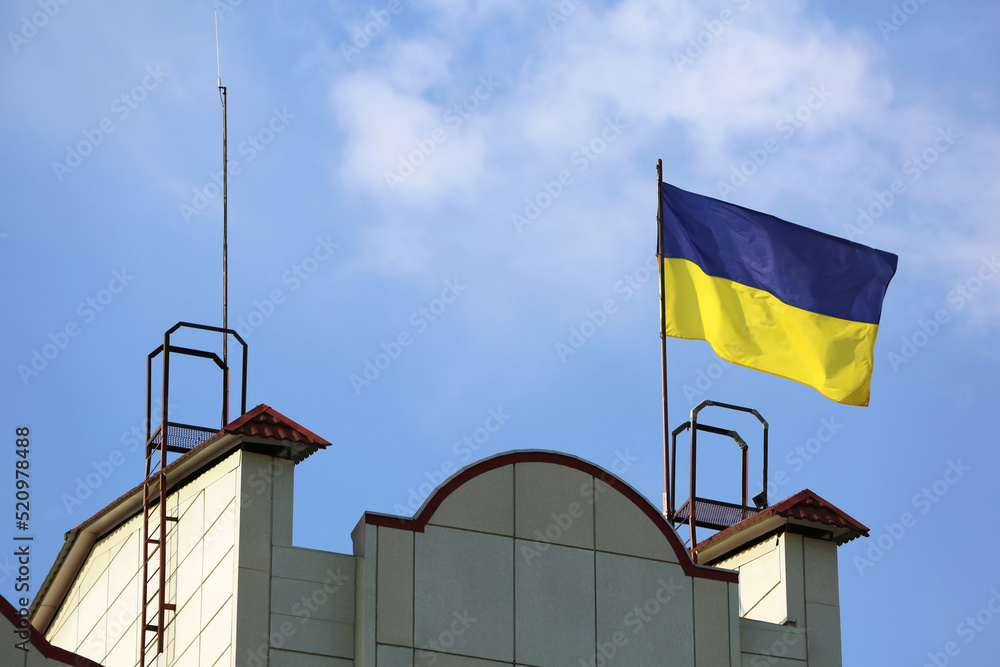 Ukrainian flag on building against blue sky Ukrainian flag on building against blue sky