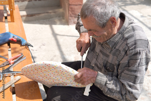 Old man fixing broken chair with screwdriver
