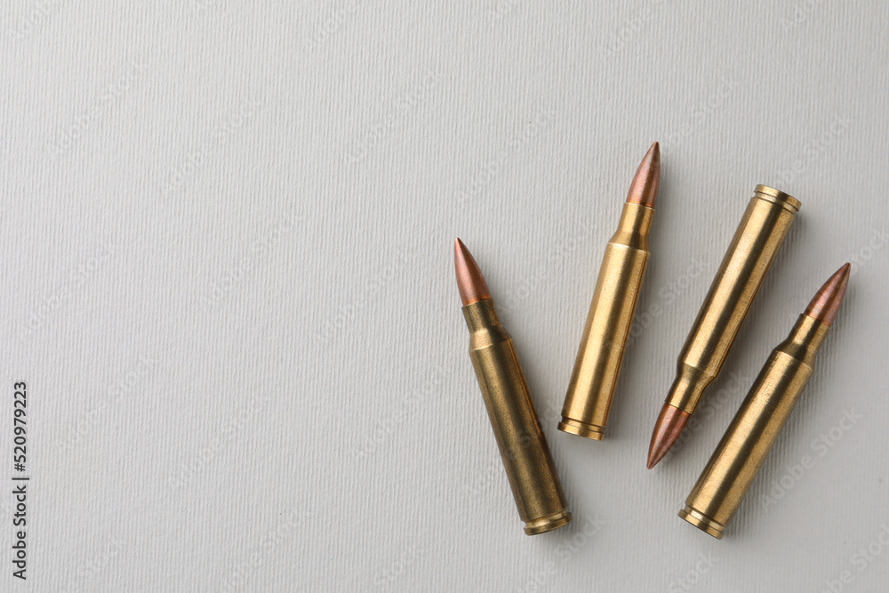 Brass bullets on white background, flat lay. Space for text Brass bullets on white background, flat lay. Space for text