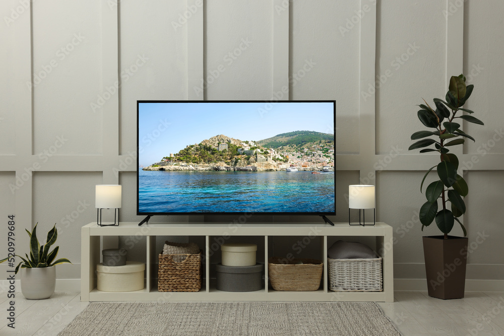 © New Africa - Modern TV set on wooden stand in room. Scene of nature themed movie on screen