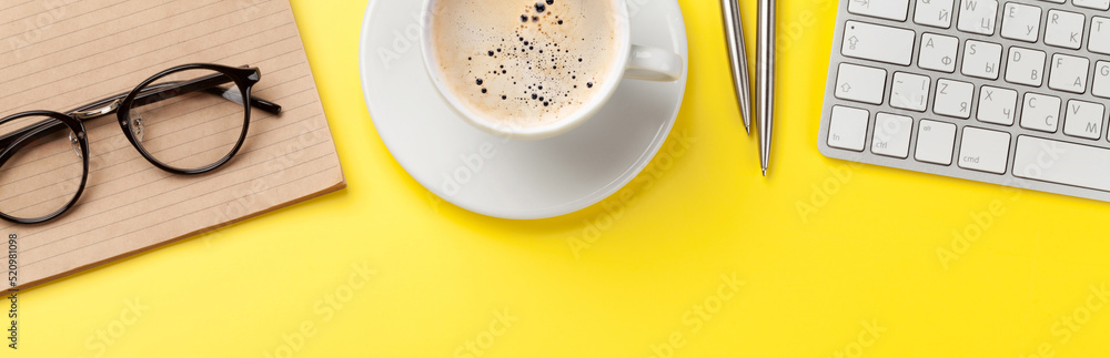 Fototapeta premium Office yellow backdrop with coffee, supplies and computer