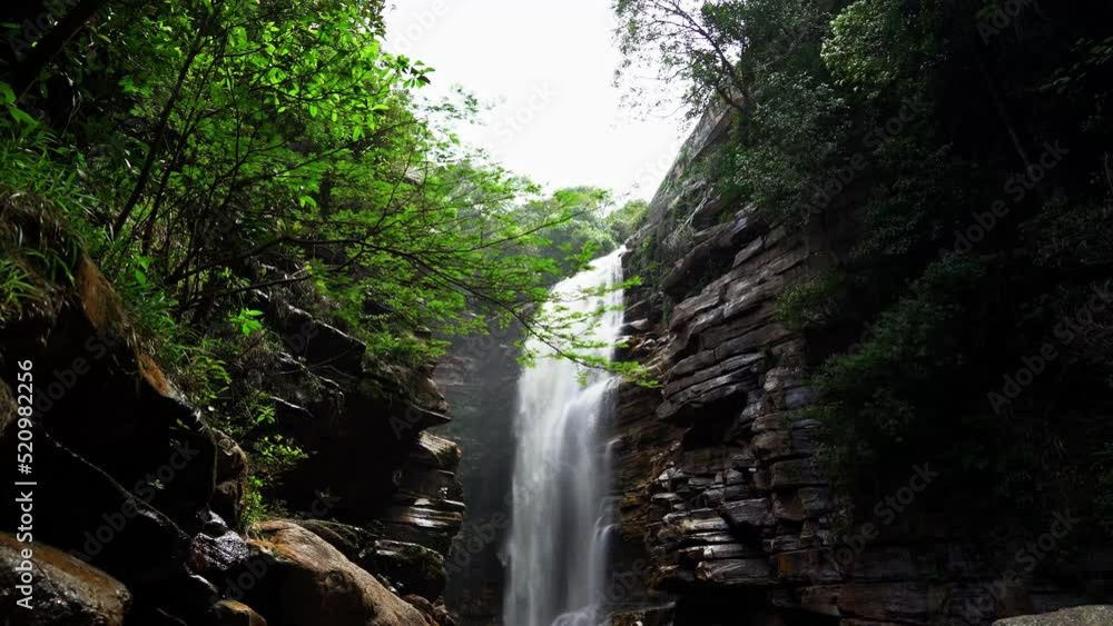 Beautiful 4K tilting down shot of the beautiful Mosquito waterfall from behind foliage and a cliff in the Chapada Diamantina National Park in the Northeastern State of Brazil Bahia. Beautiful 4K tilting down shot of the beautiful Mosquito waterfall from behind foliage and a cliff in the Chapada Diamantina National Park in the Northeastern State of Brazil Bahia.
