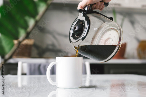 Woman brewed coffee and pours it into a mug for breakfast.