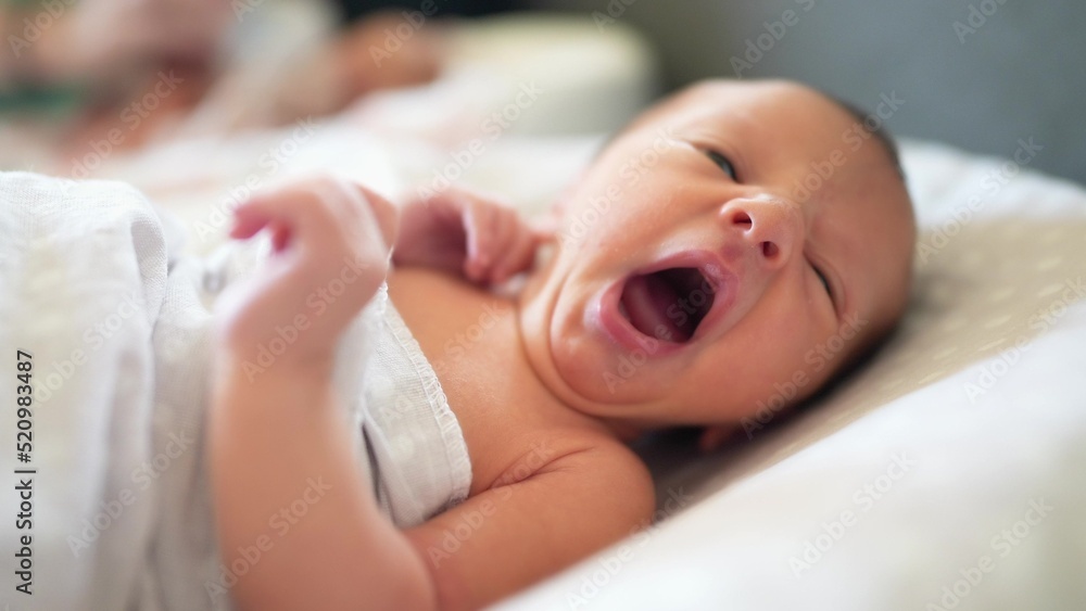 baby newborn yawns. little baby a newborn yawns of life lies in bed in
