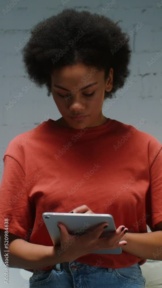 Young woman uses a digital tablet in office, then looking into the camera Young woman uses a digital tablet in office, then looking into the camera