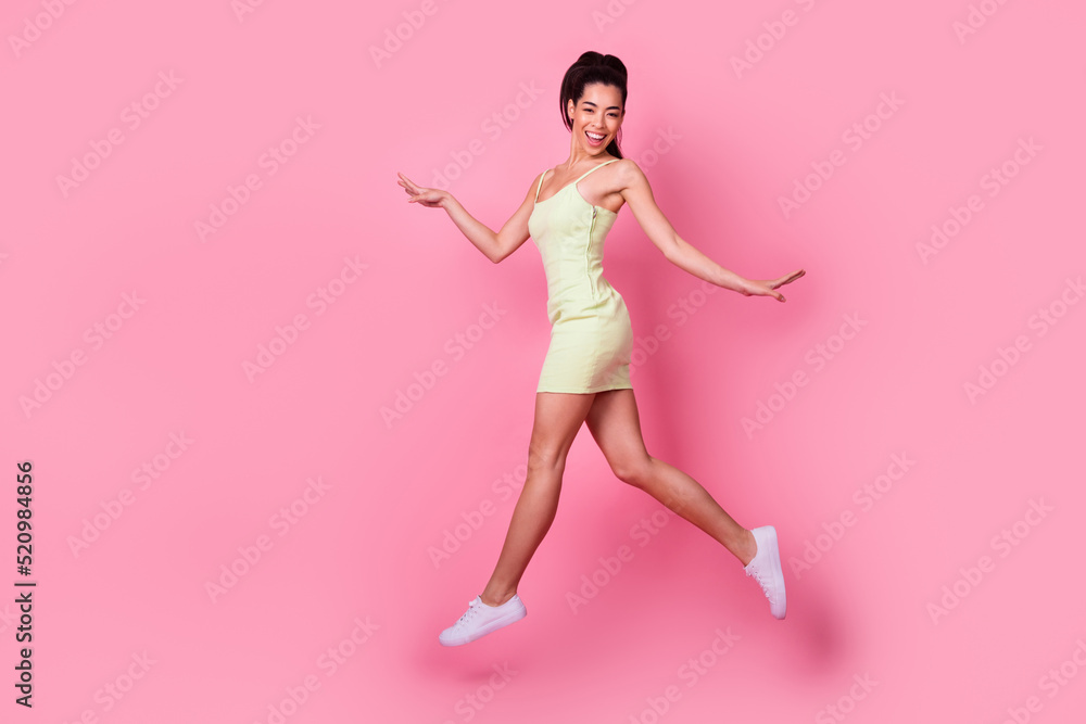 Full length photo of shiny sweet girl dressed yellow sarafan walking jumping high isolated pink color background Full length photo of shiny sweet girl dressed yellow sarafan walking jumping high isolated pink color background