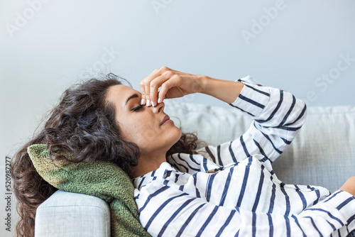 Upset depressed young woman lying on couch feeling strong headache migraine, sad tired drowsy exhausted girl resting trying to sleep after nervous tension and stress, somnolence concept