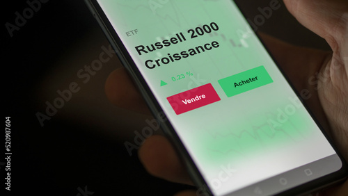 Un investisseur analyse un fonds etf russell 2000 croissance sur un graphique. Un téléphone affiche le cours de l'ETF. Texte en français francais Russell 2000 Croissance