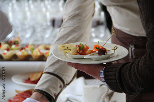 Man's hand with a plate of appetizers at the catering table 