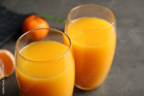 Glasses of fresh tangerine juice on grey table, closeup