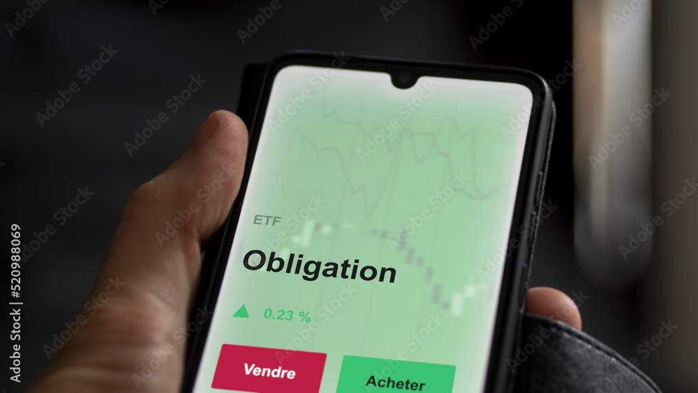 Un investisseur analyse un fonds etf obligation sur un graphique. Un téléphone affiche le cours de l'ETF. Texte en français francais Obligation Un investisseur analyse un fonds etf obligation sur un graphique. Un téléphone affiche le cours de l'ETF. Texte en français francais Obligation