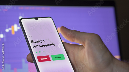 Un investisseur analyse un fonds etf énergie renouvelable sur un graphique. Un téléphone affiche le cours de l'ETF. Texte en français francais Énergie renouvelable